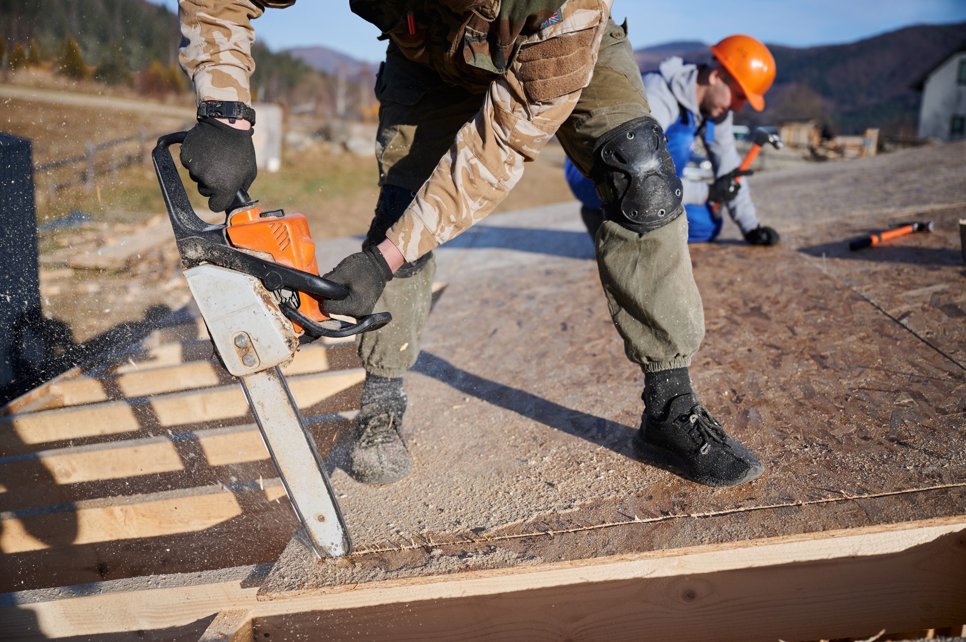 carpenter using chainsaw for cutting osb board for building wooden frame house.